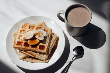 Cup of cocoa, toasts with jam and bananas on white plate
