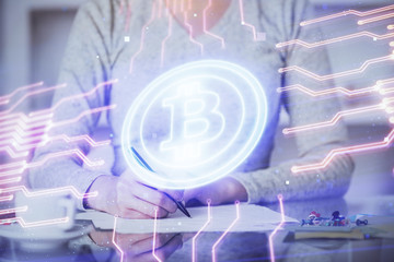 Cryptocurrency hologram over woman's hands writing background. Concept of blockchain. Multi exposure