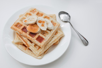 Fresh toasts with jam and bananas on white plate