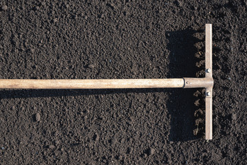 Rake on the soil of garden field top view background.