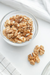  A pile of walnuts on a white background. Peeled walnuts in a glass dish.