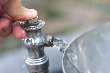 a Hand pressing the water from the park tap during the day