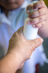 Close up of kid hand holding bottle with antiseptic cleaning gel. Kids use alcohol gel to wash hands to prevent coronavirus, Covid-19 pandemic.