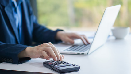 Businessman accountant using calculator and laptop for calculating finance on desk office. business financial accounting concept.