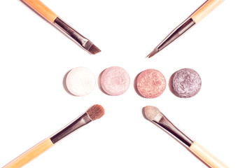 Flat lay with make up products in minimal style on white desk. Beauty background with crashed eyeshadow palette, different make up brushes. Top view, copy space.