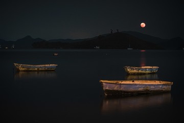 Old rusty wooden fishing boats in the lake at night