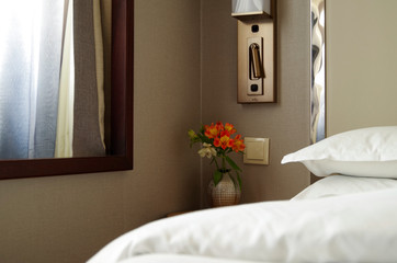 View into bedroom with king or queen double bed, night stand and flowers inside stateroom or cabin...