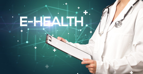 Doctor fills out medical record with E-HEALTH inscription, medical concept