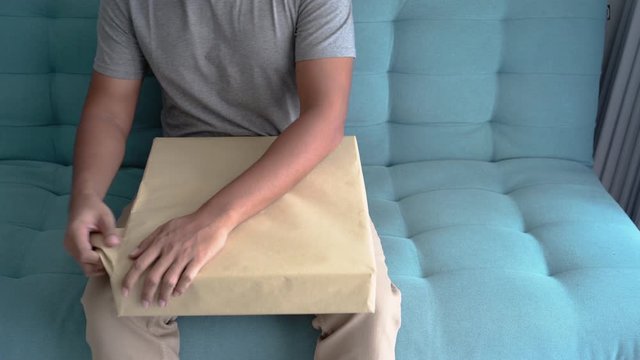 hand unboxing package sitting on a couch