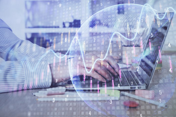 Double exposure of stock market graph with man working on laptop on background. Concept of financial analysis.