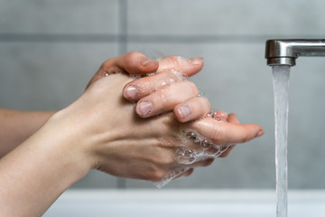 A woman washes her hands under a stream of clean water. Concept - compliance with hygiene rules,...