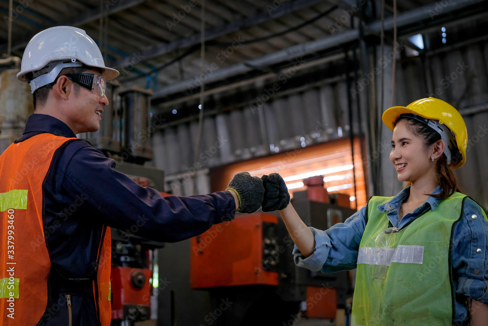 Wall mural Technician or worker man and woman show greeting action for the successful of their work and they look happy in factory area and get good industrial business.