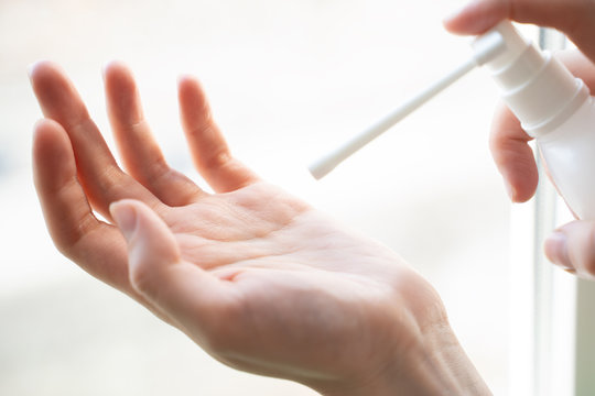 Close Up Of A Woman’s Hands Applying Alcohol Hand Sanitizer From A Small Transparent Bottle