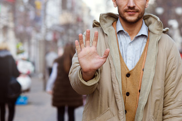A young dark and stylish man on the street shows off his palm.