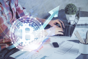 Crypto currency theme hologram with businessman working on computer on background. Concept of...
