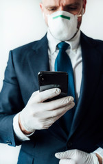 Obraz na płótnie Canvas Businessman with mask and latex gloves using smart phone