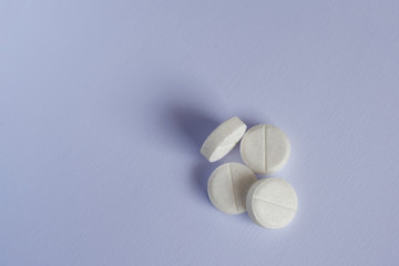 four white pills lay on blue paper