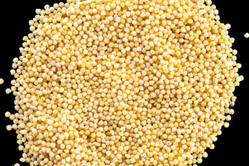 millet round yellow seeds on a black background