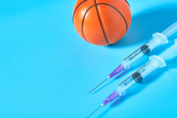 Basketball ball near syringe on blue background. Concept of doping in professional sport....
