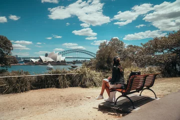 Poster Woman with Sydney Opera House & Harbour Bridge. Tourist looking at attraction, with river water. Blue sky tourism shot. Boats on river. Famous landmark. © Jam Travels