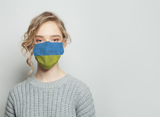 Young woman wearing a face mask with flag. Flu epidemic and virus protection concept