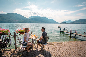 Junges Paar frühstückt direkt am Comer See in Italien  - obrazy, fototapety, plakaty