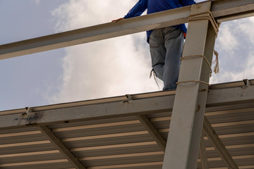 A man standing on the roofing sheet on Light steel Truss and Frame construction.