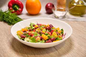 Vegetable salad with beans and orange on a white plate