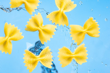 fuselini pasta on a blue background with water splashes