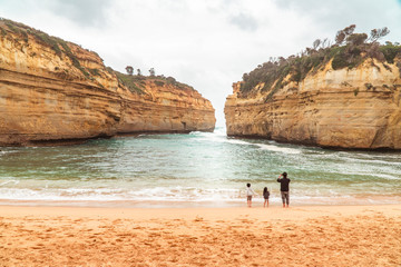 Family at beach. Rock formations with ocean sea waves on coastline. Children playing on beach on Great Ocean Road, Melbourne, Australia. Road trip. Sand, sea, holiday, vacation. Twelve Apostles