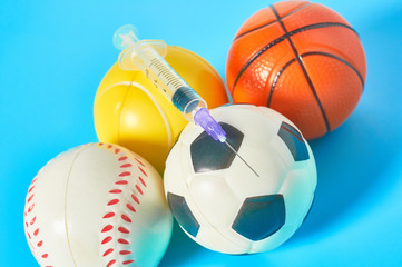 Different balls and syringe on blue background. Concept of doping in professional sport....