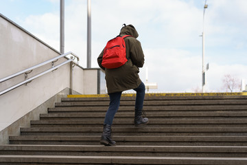 Young woman leaving the subway pedestrian underground pass. She is hurrying up. Back / rear view. Coronavirus pandemic lifestyles.