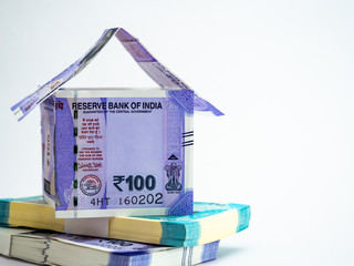 Small home made with notes and money in bundles shot on white background for loan concept.