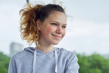 Closeup portrait of teenage girl of 14, 15 years old in gray sweatshirt