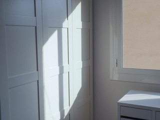 Close up of an illuminated white bedroom closet with sunlight