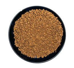Dry instant coffee in a black ceramic plate isolated on a white background