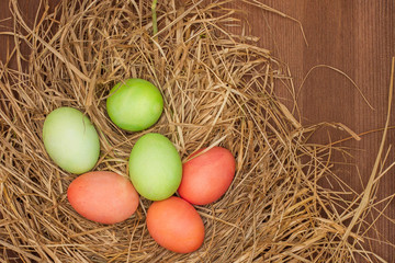 Naklejka na ściany i meble Easter, Easter eggs collection. Easter eggs on a brown wooden table. Easter eggs and hay. Orange and green eggs in the nest.