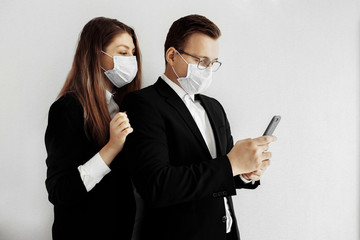 Business man and business woman looking to the phone wearing medical face mask. Stop coronavirus