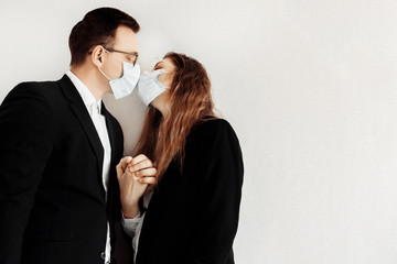 Couple in love in black suits wear medical face mask to protect each other from coronavirus. Stop pandemic 2020