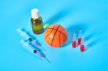 Basketball ball near syringe and ampoule, bottle on blue background. Concept of doping in sport....