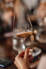 Obraz premium hands holding a glass of wine close-up in a bar. blurred background