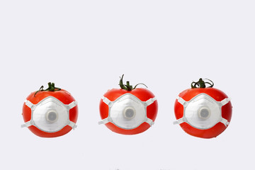 Three red tomatoes in a medical anti covid masks isolated on a white background food protection concept