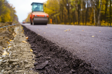 Road repair, compactor lays asphalt. Heavy special machines. Asphalt paver in operation. Side view. Closeup.