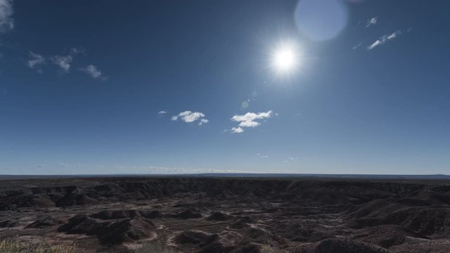An ultrawide timelapse shot of the Painted Desert in Petrified Forest National Park, as the sun moves through the shot and clouds rush past.