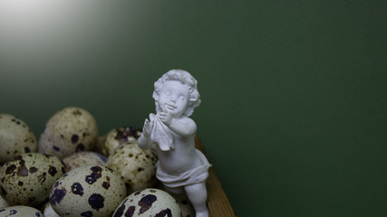 Еaster background. Delicate white angel on a green background with small eggs.