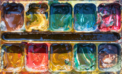 Dirty mixed old paints in the light of the sun, close-up