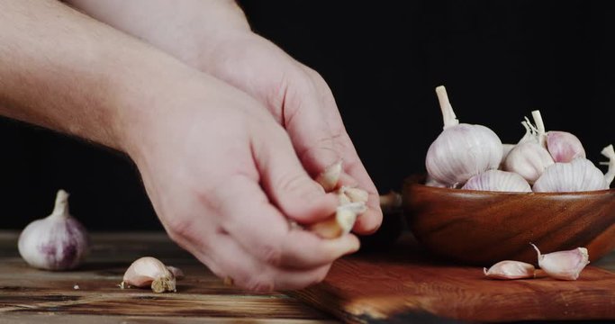 Men hands divide the garlic into slices.