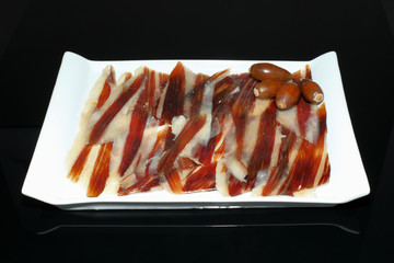 Iberian ham dish with acorns on black background