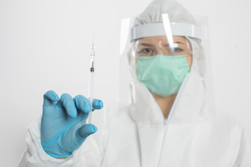 A young apprentice wearing a mask and protective suit is holding a syringe in her hand.