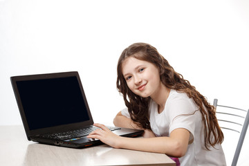 Cute schoolgirl sitting at a laptop on a white background